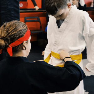 Douvris Barrhaven sensei tying yellow belt for member